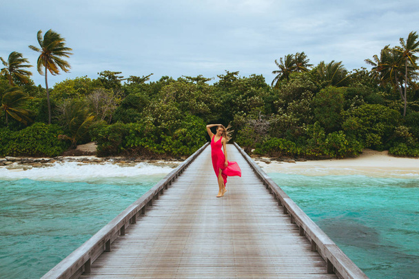 Girl in a long pink dress walking on the pier. - Valokuva, kuva
