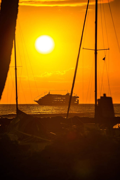 Amazing sunset view over the cruise ship in the Pacific ocean from the beach with palms. - Photo, image