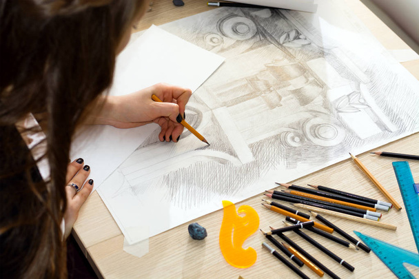 Τα χέρια του αρχιτέκτονα φοιτητής με ένα μολύβι προετοιμασία ένα μοτίβο του φωτός και της σκιάς, σχεδιασμός κάγγελο κινηματογραφήσεων σε ένα ξύλινο τραπέζι - Φωτογραφία, εικόνα