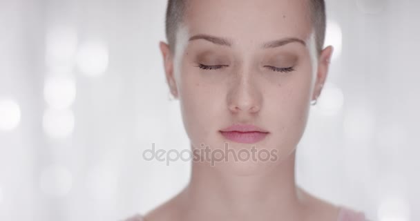 Attractive young woman opens her eyes in front of a white background - Video