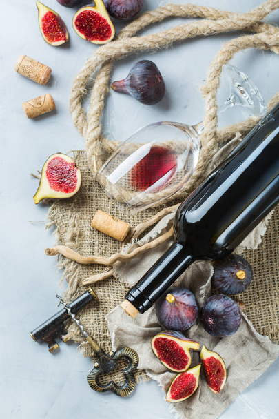Botella, sacacorchos, copa de vino tinto, higos en una mesa
 - Foto, Imagen