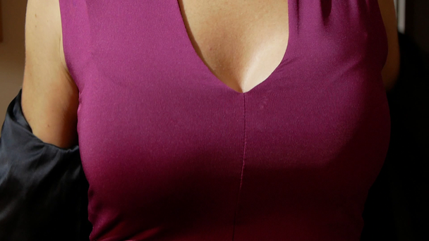 μια γυναίκα με ένα όμορφο στήθος τοποθετεί σε ένα μαύρο σακάκι - Πλάνα, βίντεο