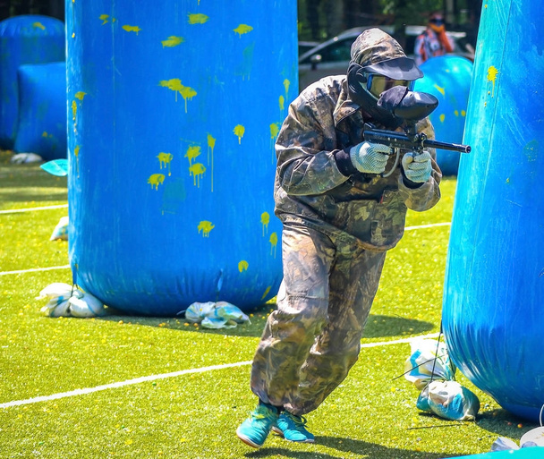Paintball sportovní hráč v ochranné uniformě a masky hrát s pistolí venku - Fotografie, Obrázek