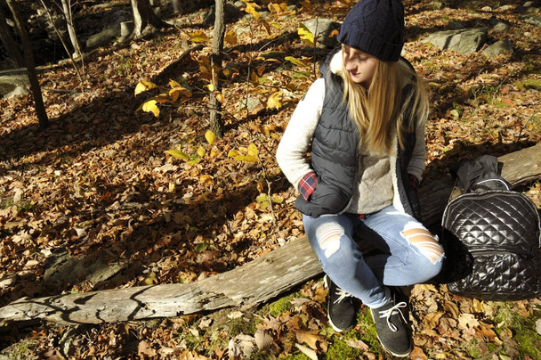 Girl is sitting in autumn forest in the mountains. Hiking and traveling - Zdjęcie, obraz