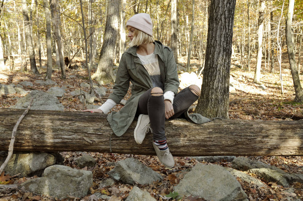 Girl is sitting in autumn forest in the mountains. Hiking and traveling - Photo, Image