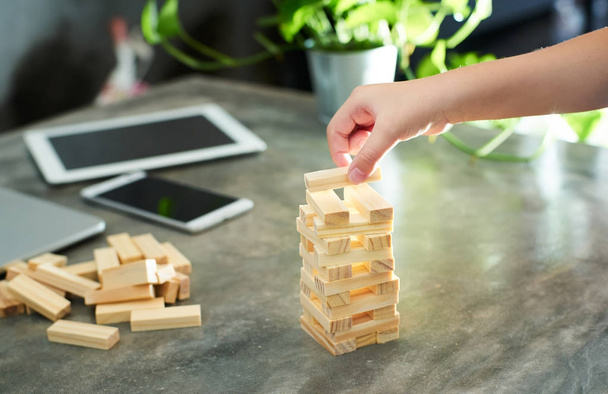 Hand of kid playing a blocks wood tower game of architectural project and blur background .Selected focusing . - 写真・画像