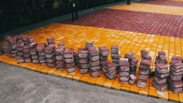Vícebarevné chodník dlaždice v dětský park leží na zemi připravený pro pokládku - Záběry, video