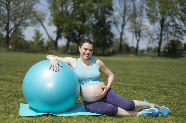 Красивая молодая беременная женщина упражняется с фитболом в тренажерном зале
 - Фото, изображение