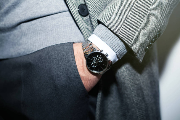 Closeup fashion image of luxury watch on wrist of man.body detail of a business man.Man's hand in wool blue jacket,in dark blue pants pocket closeup.Casual outfit. Tonal in a business suit close up - Photo, Image