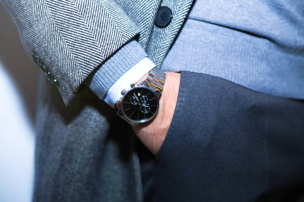 Closeup fashion image of luxury watch on wrist of man.body detail of a business man.Man's hand in wool blue jacket,in dark blue pants pocket closeup.Casual outfit. Tonal in a business suit close up - Zdjęcie, obraz