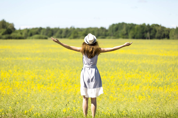 Güzel genç kız şapkalı bir çayır rüzgarlı bir günde arıyorsunuz bir - Fotoğraf, Görsel