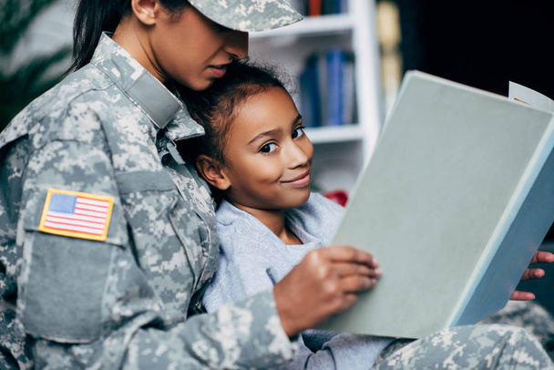 daughter and female soldier reading book - Foto, imagen