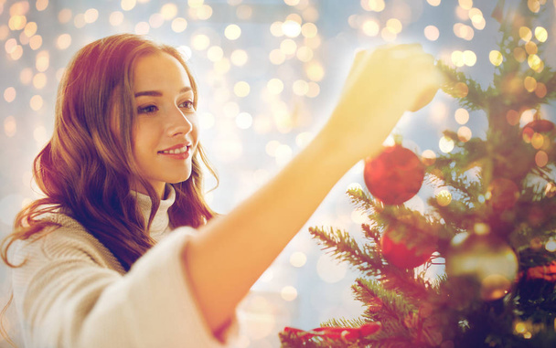 happy young woman decorating christmas tree - Fotó, kép