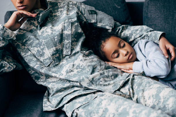 mother in military uniform with sleeping daughter  - Fotoğraf, Görsel