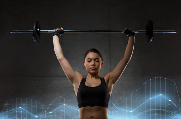 young woman flexing muscles with barbell in gym - Foto, imagen