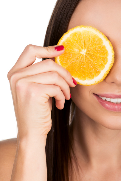 woman covering eye with slice of orange - Foto, afbeelding