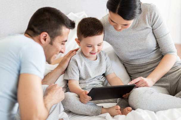 happy family with tablet pc in bed at home - Φωτογραφία, εικόνα