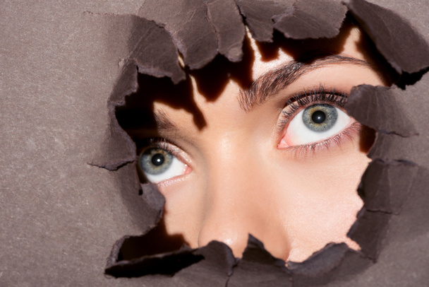 woman peeking out of hole in paper - Фото, зображення