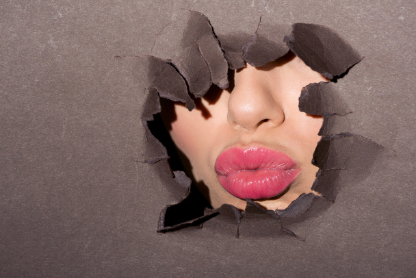lèvres roses de femme dans un trou de papier
 - Photo, image