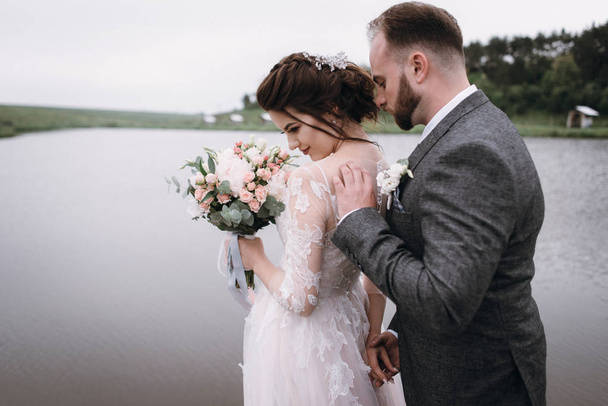 Newlyweds walk near lake on their wedding day - Photo, Image