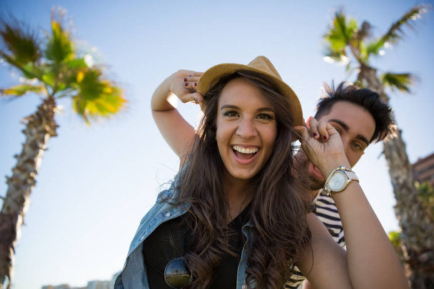 Laughing woman wearing hat and her boyfriend behind her - Fotó, kép