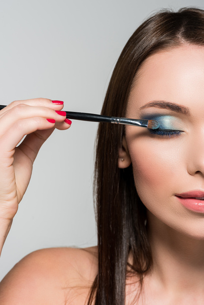 young woman applying eyeshadow - Foto, afbeelding