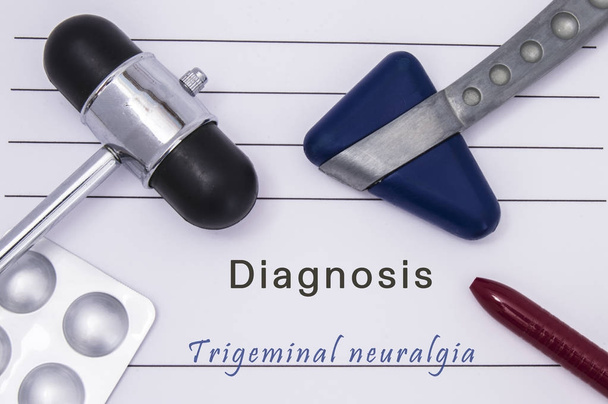 Medisch formulier met tekst diagnose trigeminus neuralgie, twee medische neurologische reflex hamers, geneeskunde pillen in een doordrukverpakking en een balpen afgedrukt op de tafel in de spreekkamer - Foto, afbeelding