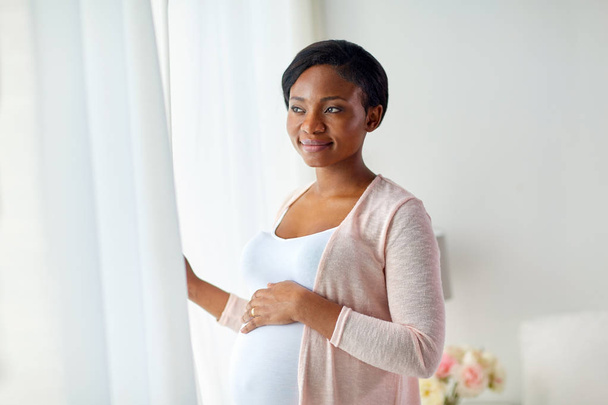 mujer embarazada mirando a través de la ventana en casa
 - Foto, imagen