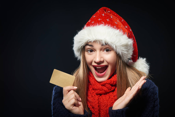 Surprised girl in Santa hat with blank credit card - Fotoğraf, Görsel