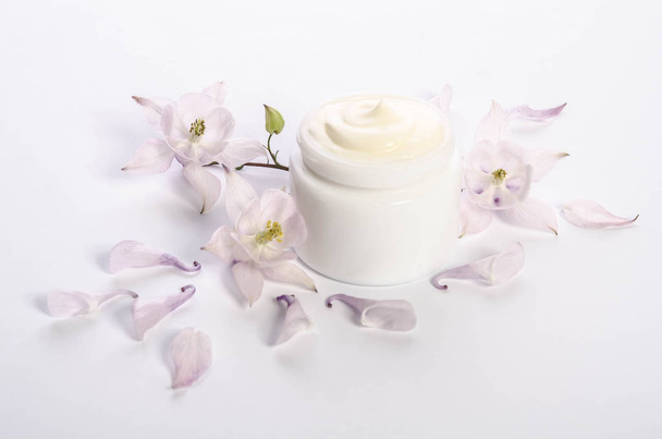 Cute flowers and petals and a jar of natural body cream - Foto, afbeelding
