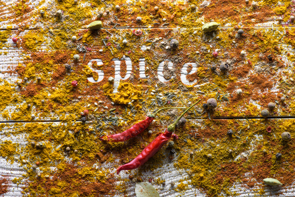 verspreide specerijen op tafel en woord Spice - Foto, afbeelding