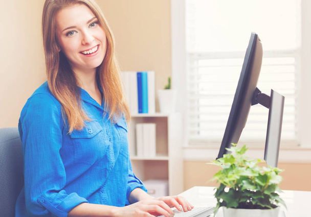 Happy young woman using a her computer - Φωτογραφία, εικόνα