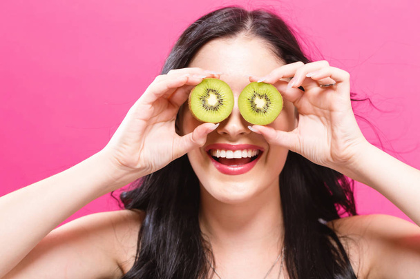  Happy young woman holding kiwis  - Foto, afbeelding