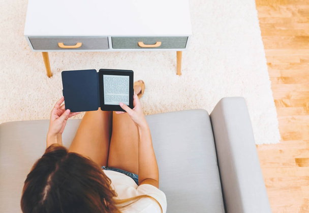 Молода жінка читає у своїй вітальні
 - Фото, зображення