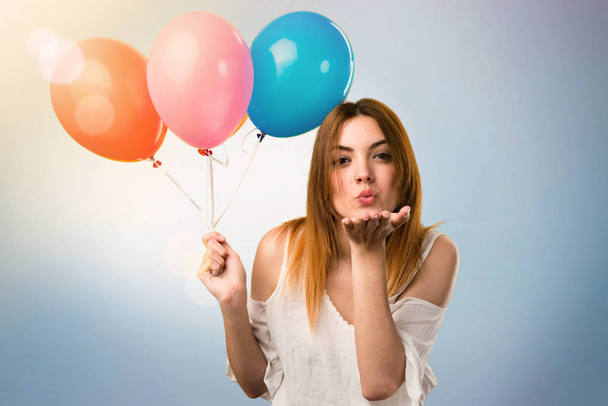 Beautiful young girl holding a balloon and sending a kiss on unf - 写真・画像