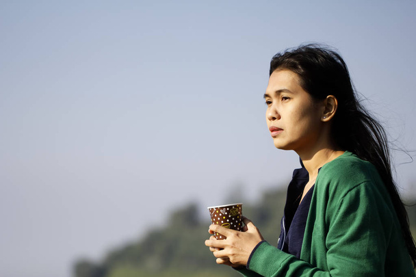 Šálek kávy v ruce ženy proti modré obloze - Fotografie, Obrázek