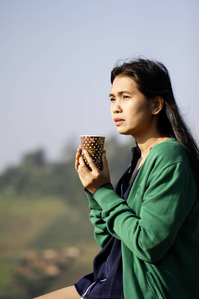 Kaffeetasse in der Hand einer Frau vor blauem Himmel - Foto, Bild
