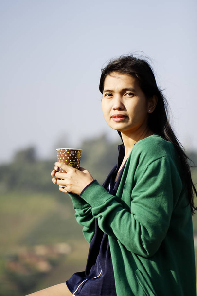 Kaffeetasse in der Hand einer Frau vor blauem Himmel - Foto, Bild