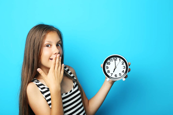 Portrait of beautiful girl with round clock on blue background - Photo, image