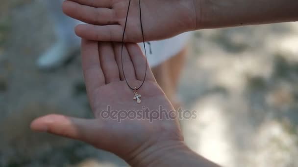 Nelle mani umane giace una piccola croce d'oro ortodossa su una corda
. - Filmati, video