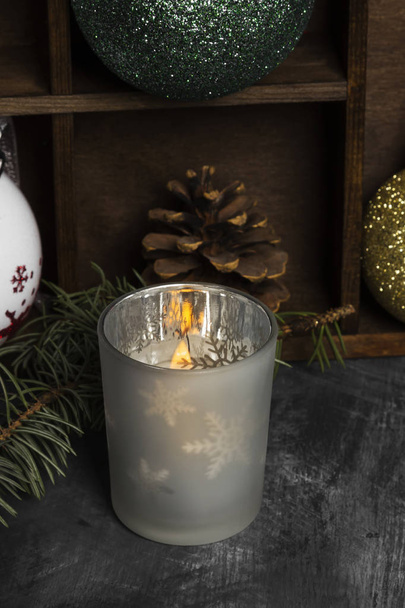 Burning candle in candlesticks and Christmas attributes on a dar - Photo, image