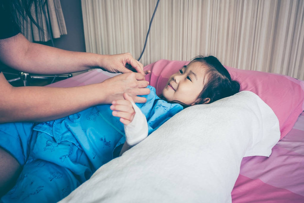Asian child admitted in hospital with saline intravenous drip on hand. - Photo, Image