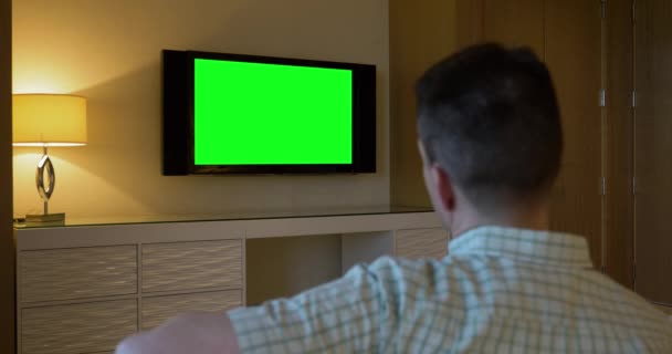 Ο άνθρωπος ρολόγια πράσινη οθόνη τηλεόραση στο δωμάτιο του ξενοδοχείου πολυτελείας - Πλάνα, βίντεο