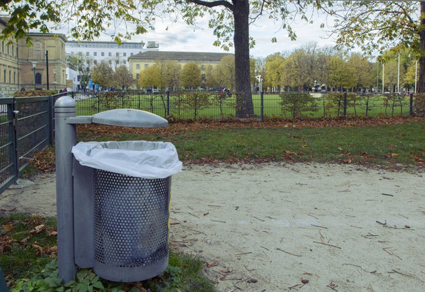 Monachium, Niemcy - 2 listopada 2017: Kosz na śmieci w parku na chodnik / trawy w pobliżu Alte Pinakothek, Monachium. - Zdjęcie, obraz