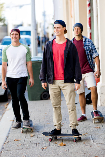 Teenage friends walking at the street with skateboards - Fotó, kép