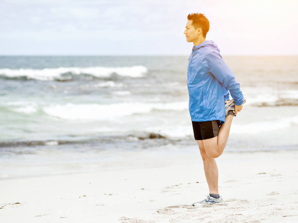 Young man doing exercise at the beach - Valokuva, kuva