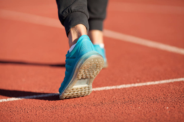 Athlete runner feet running on road closeup on shoe. Man fitness jog workout wellness concept. Man runner legs and shoes in action on road - Φωτογραφία, εικόνα