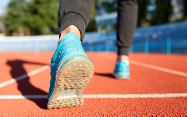 Der Sportler läuft mit den Füßen auf der Straße in Nahaufnahme auf Schuhen. Mann Fitness Jog Workout Wellness-Konzept. Läuferbeine und Schuhe im Einsatz auf der Straße - Foto, Bild