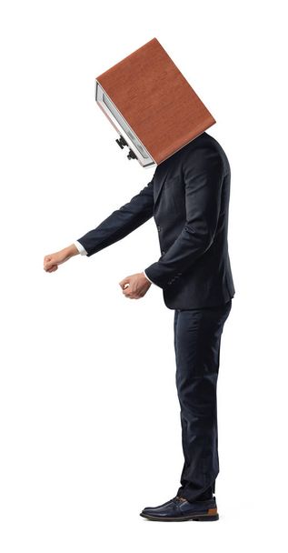 A single isolated businessman stands bending down and pulling at something in a side view with a TV box on his head. - Foto, Bild