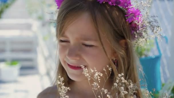 Portrait of cute little girl with wildflowers in the hands looking at camera 4K - Imágenes, Vídeo